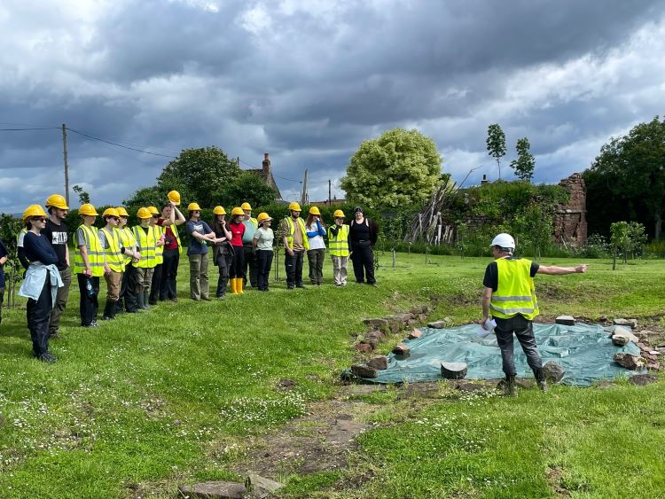 students looking over fieldsite with instruction from lead archaeologist